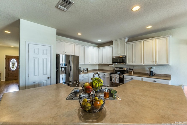 kitchen with visible vents, recessed lighting, appliances with stainless steel finishes, white cabinets, and a textured ceiling