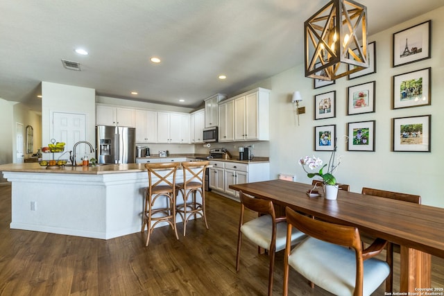 kitchen with visible vents, appliances with stainless steel finishes, white cabinetry, and dark wood-style flooring