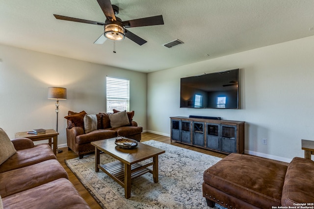 living area with wood finished floors, visible vents, baseboards, ceiling fan, and a textured ceiling