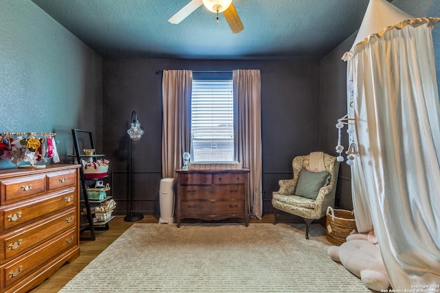 living area with a textured ceiling, wood finished floors, and a ceiling fan