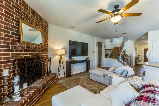 living room with visible vents, a brick fireplace, stairs, wood finished floors, and arched walkways