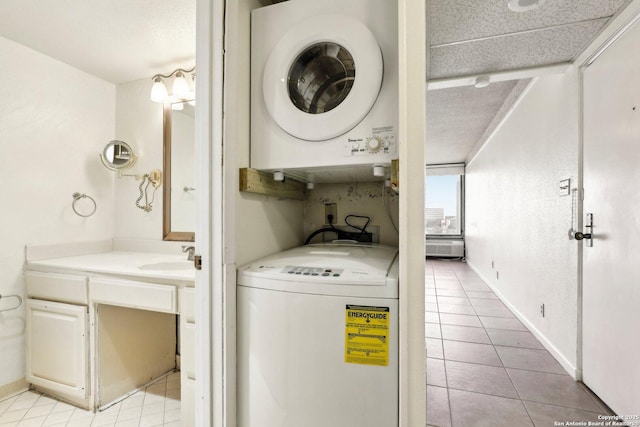 laundry area featuring baseboards, stacked washing maching and dryer, laundry area, light tile patterned flooring, and a sink