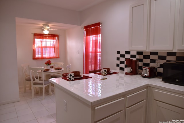 kitchen featuring tile countertops, plenty of natural light, a peninsula, and black microwave