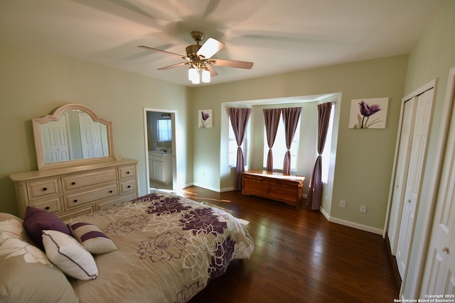 bedroom featuring dark wood-style floors, baseboards, ensuite bathroom, and ceiling fan