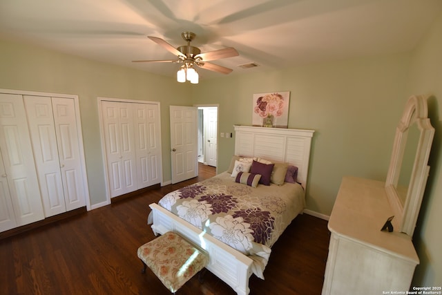 bedroom featuring visible vents, baseboards, two closets, and dark wood-style flooring