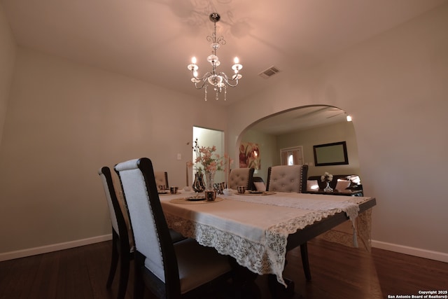 dining space featuring dark wood finished floors, visible vents, a chandelier, and baseboards