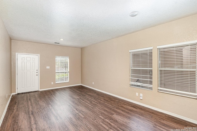 empty room featuring dark wood-style floors, baseboards, and a textured ceiling