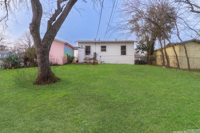 rear view of house with crawl space, a lawn, and fence