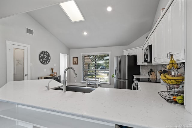 kitchen featuring visible vents, light stone countertops, appliances with stainless steel finishes, white cabinets, and a sink