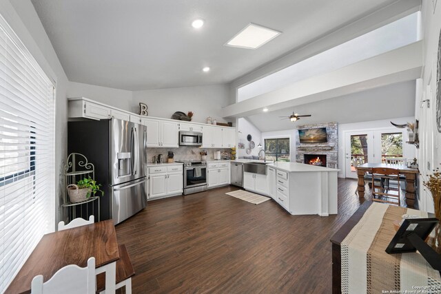 kitchen with a peninsula, lofted ceiling, a sink, stainless steel appliances, and light countertops