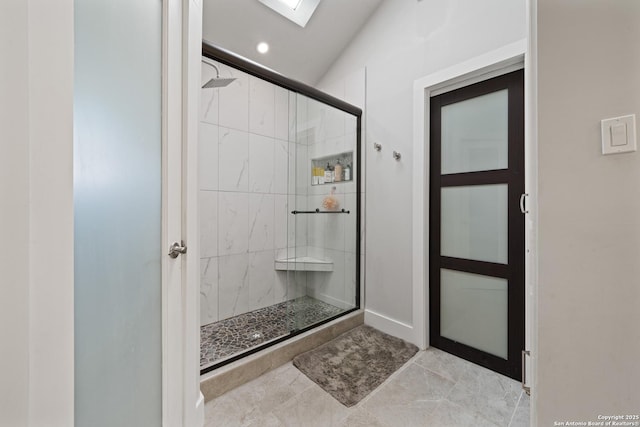 full bathroom featuring lofted ceiling with skylight and a shower stall