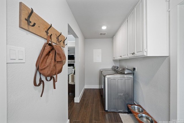 clothes washing area featuring visible vents, dark wood-style floors, washing machine and dryer, cabinet space, and baseboards