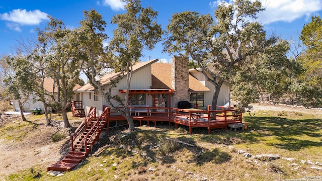 back of property featuring stairs, roof with shingles, a chimney, a yard, and a deck