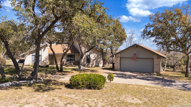 view of front of house featuring stone siding, concrete driveway, and an outdoor structure