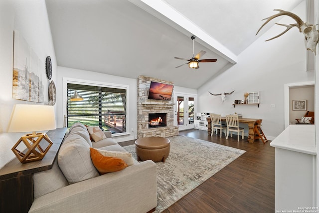 living room with dark wood-type flooring, beam ceiling, a stone fireplace, high vaulted ceiling, and a ceiling fan