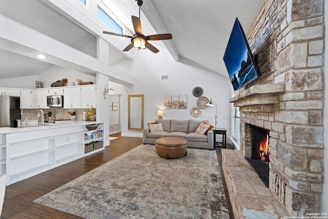 living room with dark wood-style floors, visible vents, high vaulted ceiling, a fireplace, and ceiling fan