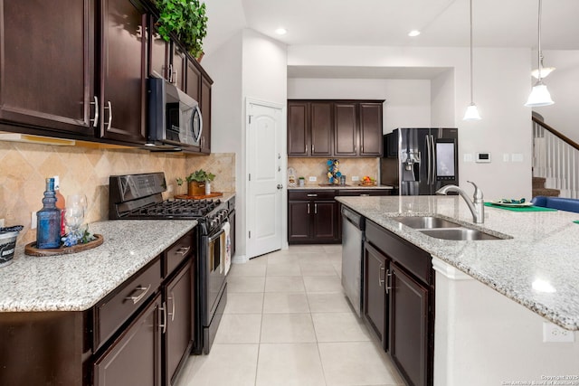 kitchen featuring dark brown cabinets, pendant lighting, light tile patterned floors, stainless steel appliances, and a sink