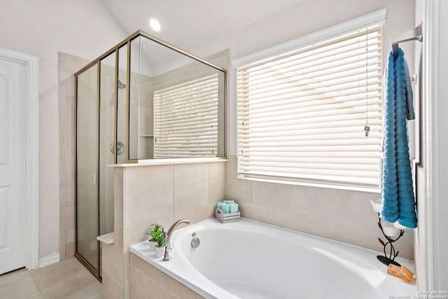 bathroom with a stall shower, tile patterned flooring, and a bath