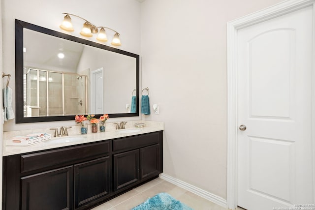 bathroom featuring double vanity, a tile shower, tile patterned floors, and a sink