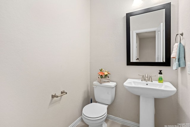 half bathroom with toilet and baseboards