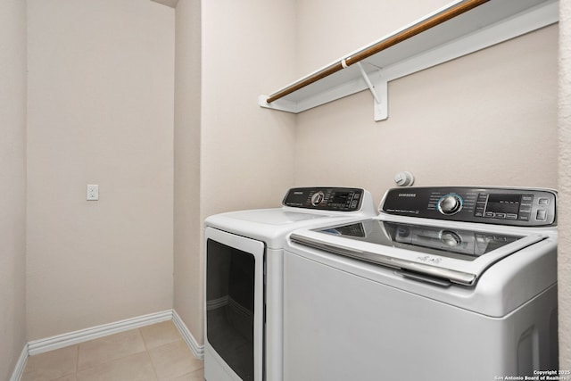 washroom with light tile patterned floors, laundry area, washer and dryer, and baseboards