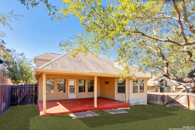 back of house with a fenced backyard, a lawn, a patio, and roof with shingles