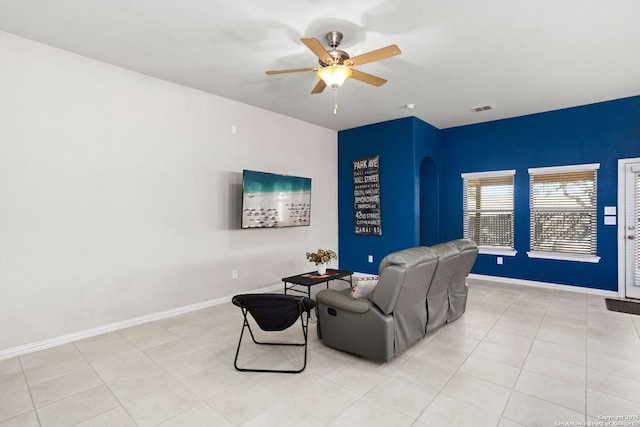 interior space featuring light tile patterned floors, baseboards, visible vents, arched walkways, and ceiling fan