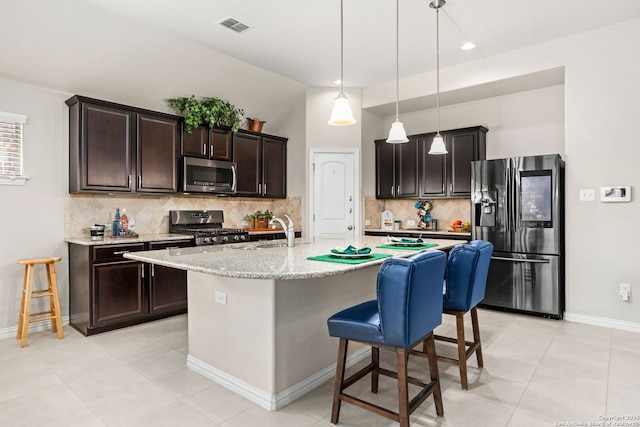 kitchen with visible vents, dark brown cabinets, light stone countertops, a breakfast bar, and appliances with stainless steel finishes