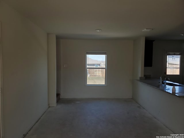 unfurnished living room with a wealth of natural light, visible vents, and a sink