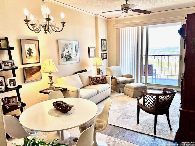 living room featuring ceiling fan with notable chandelier, a textured ceiling, wood finished floors, and ornamental molding