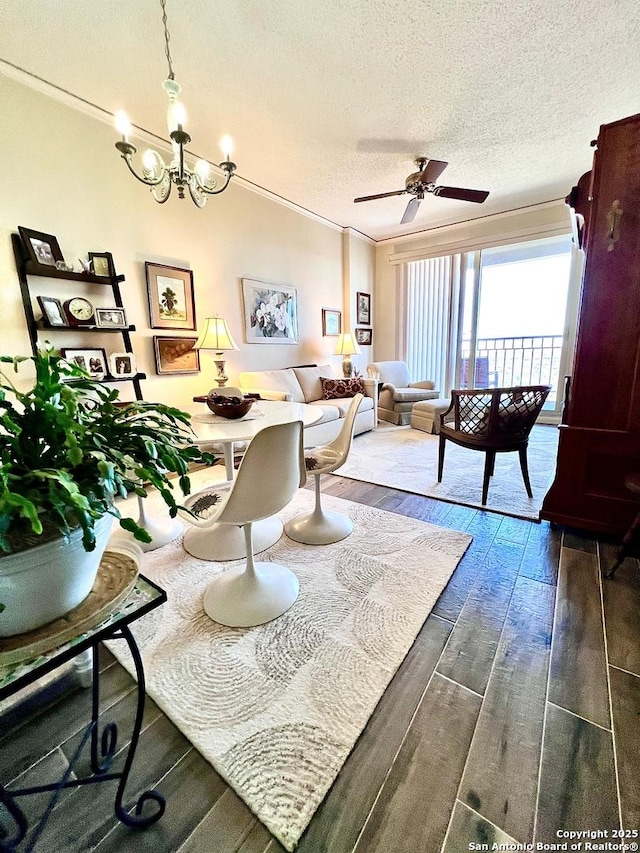 living area with a textured ceiling, ceiling fan with notable chandelier, wood finished floors, and ornamental molding