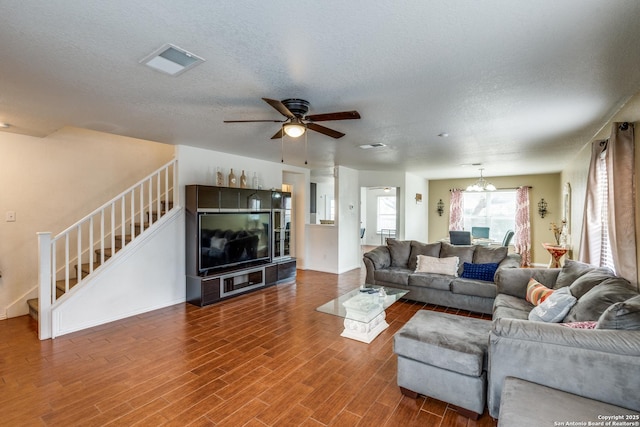 living area with visible vents, stairway, a textured ceiling, and wood finished floors