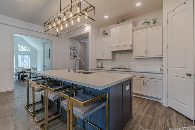 kitchen featuring white gas cooktop, a sink, decorative backsplash, light countertops, and white cabinets