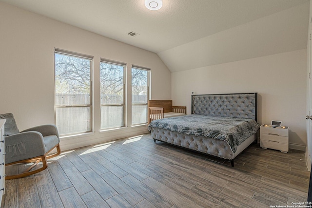 bedroom with lofted ceiling, wood finished floors, and visible vents