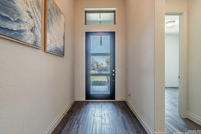 foyer featuring dark wood-style floors, baseboards, and a textured wall