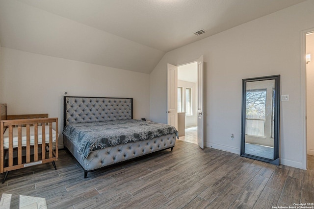 bedroom with visible vents, lofted ceiling, baseboards, and wood finished floors