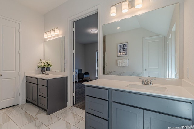 bathroom featuring lofted ceiling, two vanities, and a sink