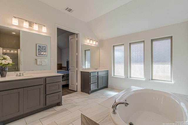 full bathroom featuring visible vents, two vanities, a sink, lofted ceiling, and a bath