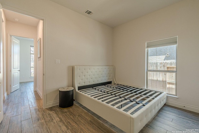 bedroom with wood finished floors, visible vents, and baseboards