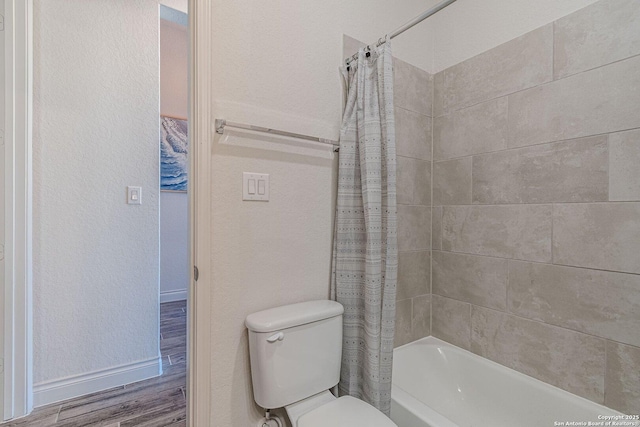 full bathroom featuring wood finished floors, baseboards, shower / tub combo, toilet, and a textured wall