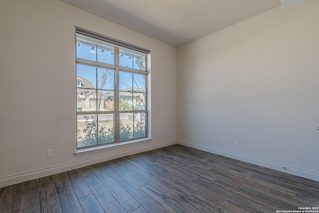 empty room featuring baseboards and dark wood-style flooring