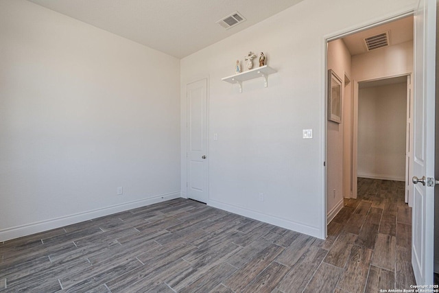 empty room with dark wood finished floors, baseboards, and visible vents