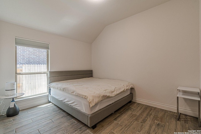 bedroom featuring dark wood-type flooring, baseboards, and lofted ceiling