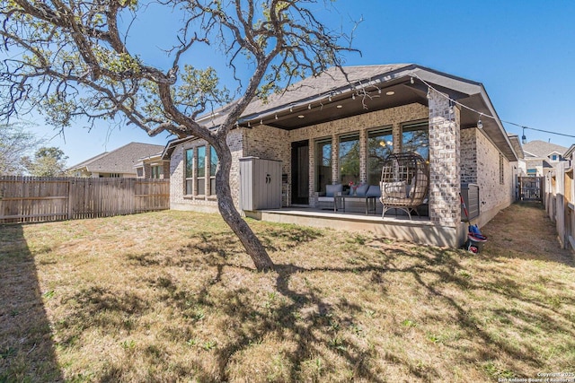 back of property featuring brick siding, a patio, a fenced backyard, and a lawn