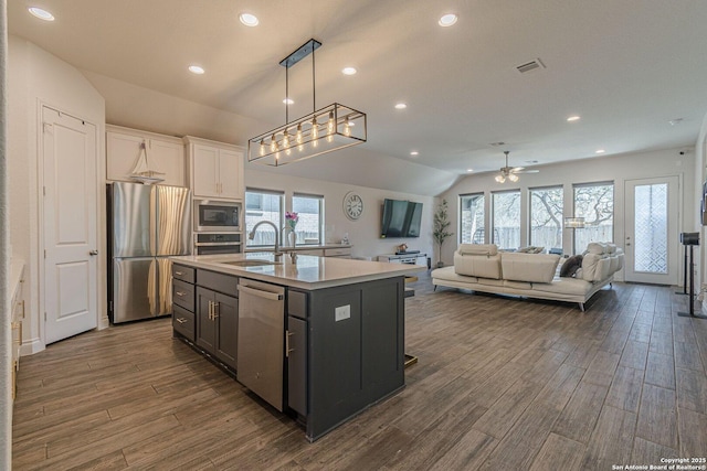 kitchen with visible vents, lofted ceiling, a sink, stainless steel appliances, and dark wood-type flooring