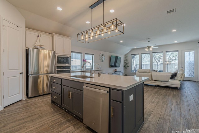 kitchen featuring visible vents, a sink, appliances with stainless steel finishes, white cabinetry, and dark wood-style flooring