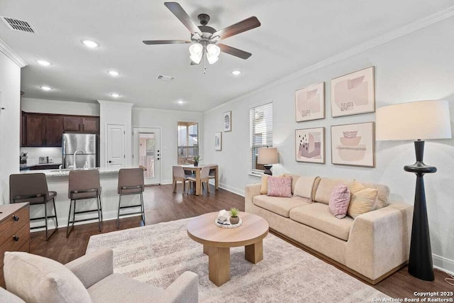 living room with dark wood-style floors, visible vents, and crown molding