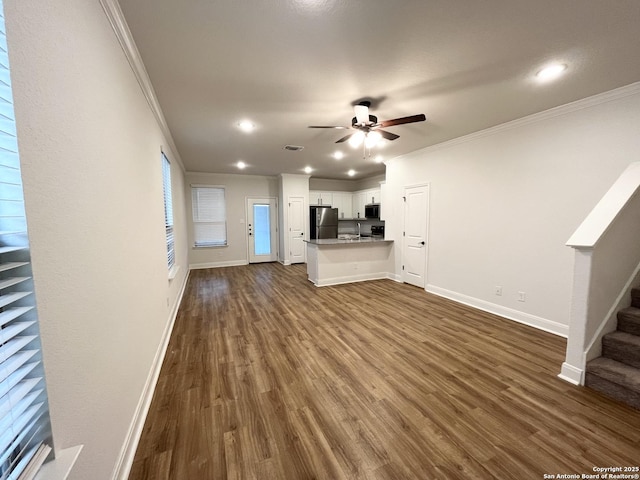 unfurnished living room with crown molding, stairway, and dark wood-style flooring