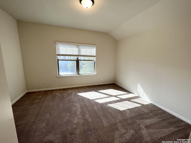 empty room featuring lofted ceiling, baseboards, and carpet floors