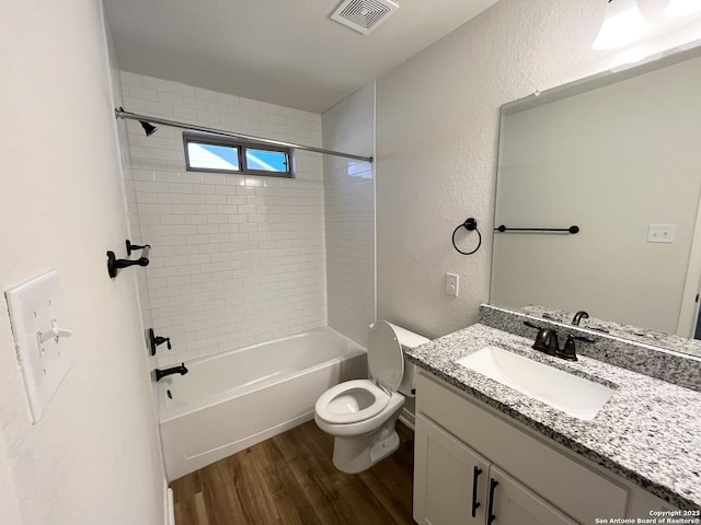 full bathroom featuring visible vents, toilet, wood finished floors, a textured wall, and vanity